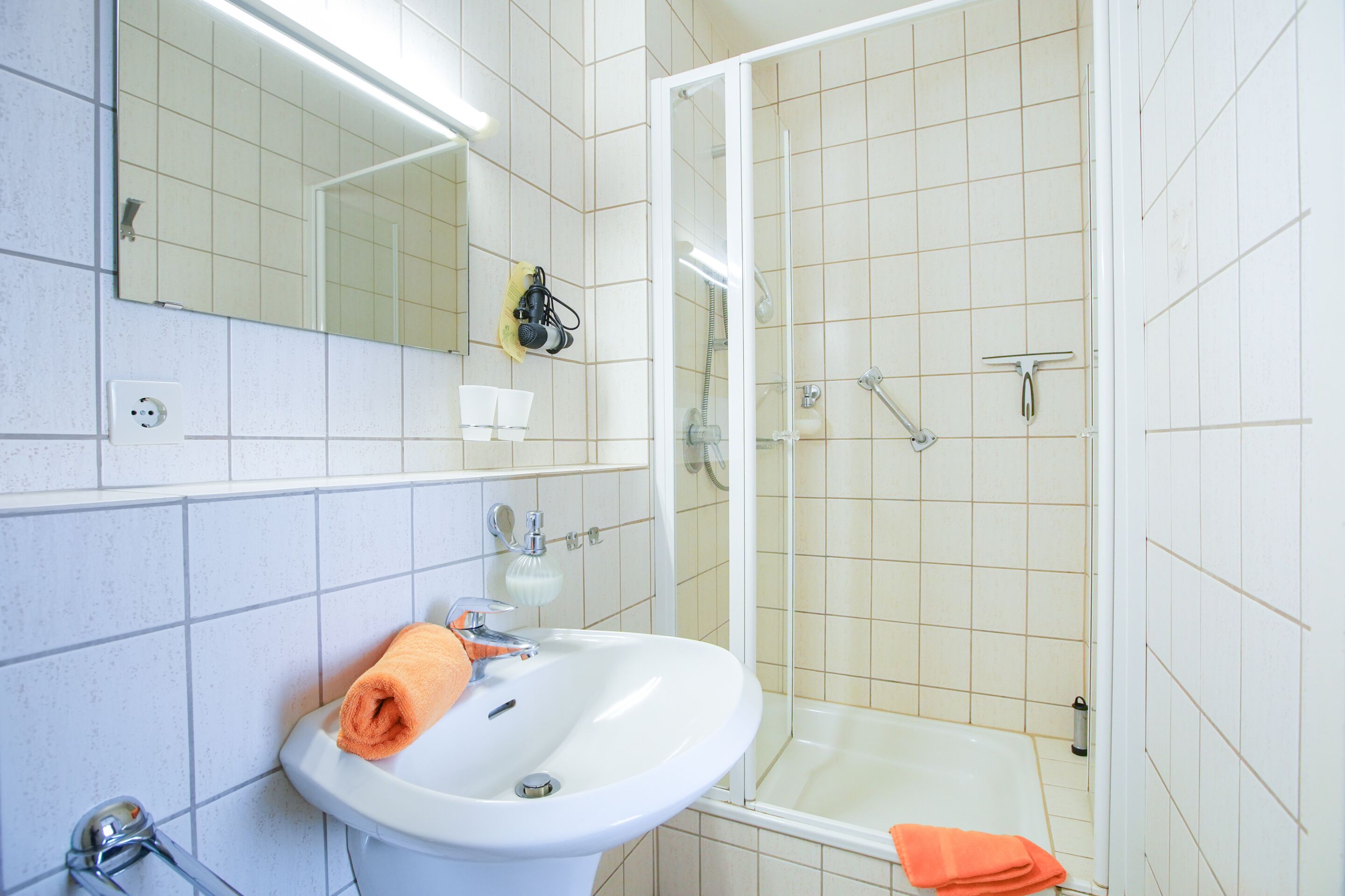 A bathroom with a sink, mirror, and shower.