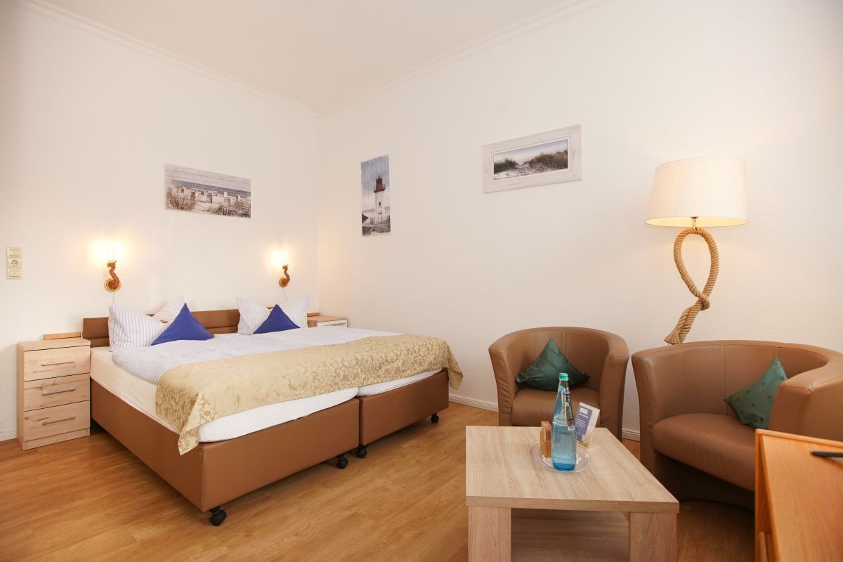 Un dormitorio con cama, mesitas de noche, lámpara, silla y una mesa.