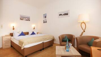 Ein Schlafzimmer mit einem Bett, Nachttischen, einer Lampe, einem Sessel und einem Tisch.