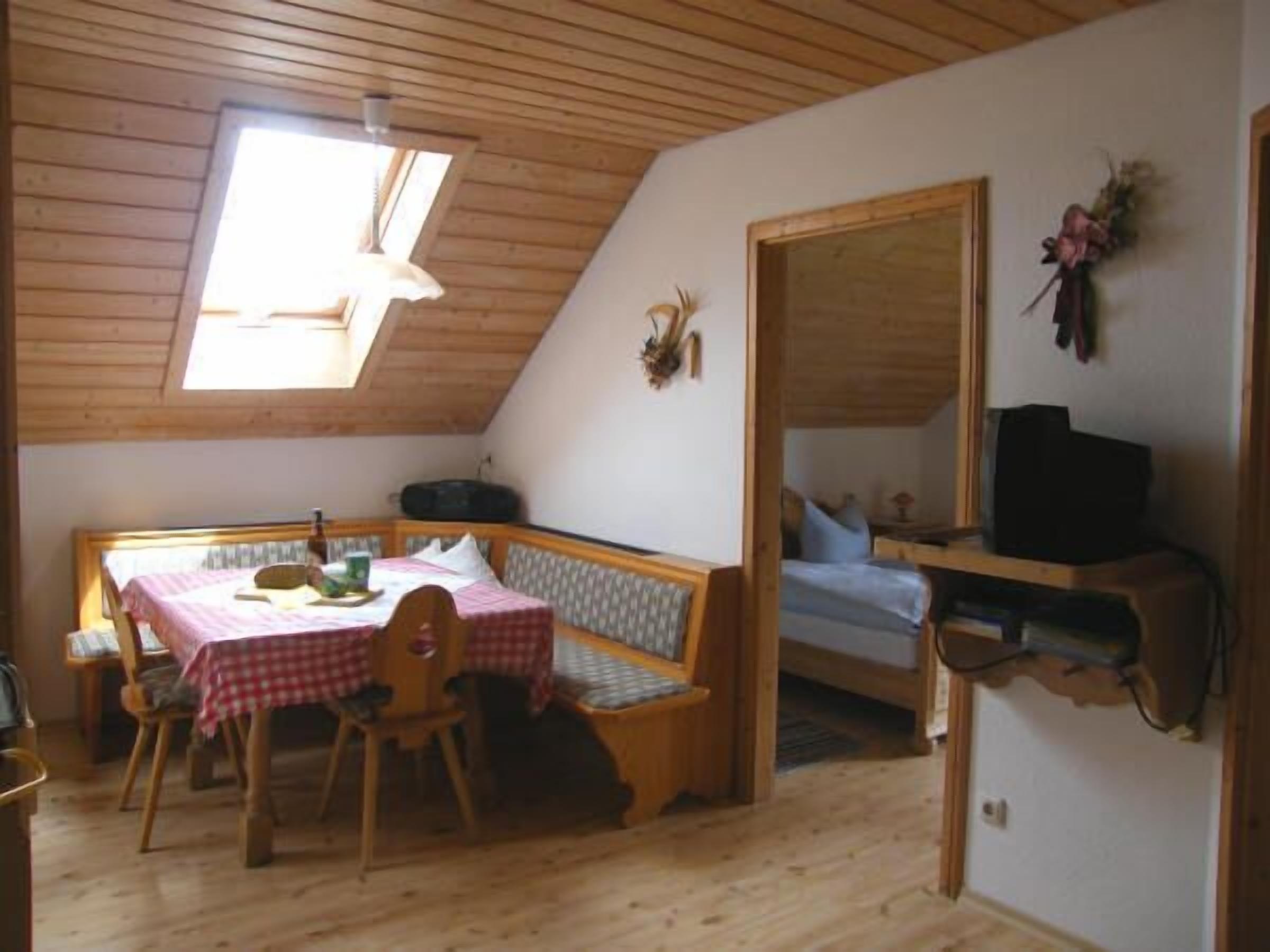 Een knus vertrek met een houten plafond, een tafel met stoelen, een bank en een bed.