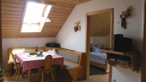 Et hyggeligt rum med træloft, et bord med stole, en bænk og en seng.