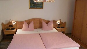 A double bed with a wooden headboard, two bedside lamps, and a single pink pillow. - Bergblick94m², EG, 2 Schlafzimmer, Sat-tv, Terrasse, Max. 4 Personen (Anger)