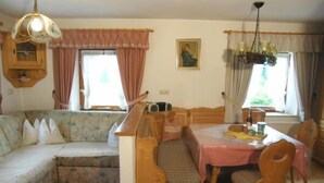 Ein gemütliches Wohnzimmer mit einer Couch, einem Esstisch mit Stühlen, einer Holzbank und einer Pendelleuchte.
