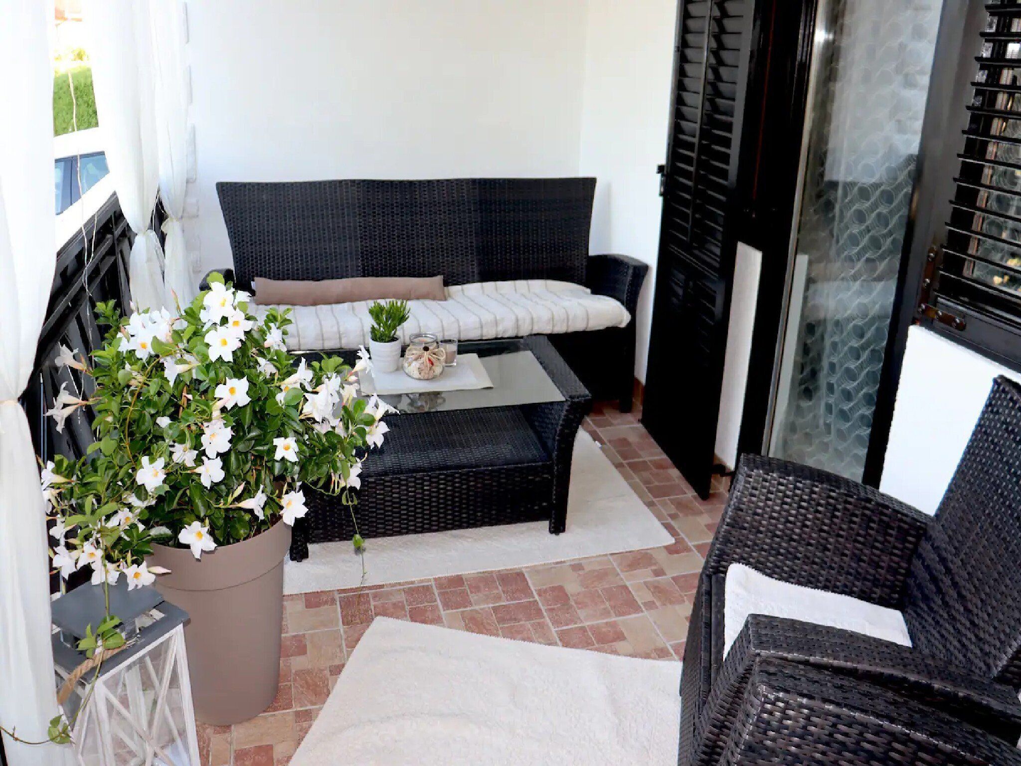 A cozy outdoor seating area with a sofa, a small table, and a potted plant.