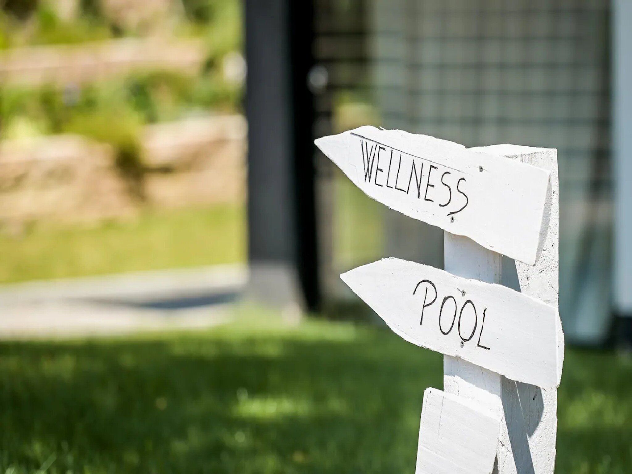 A directional signpost with 'WELLNESS' and 'POOL' written on it.