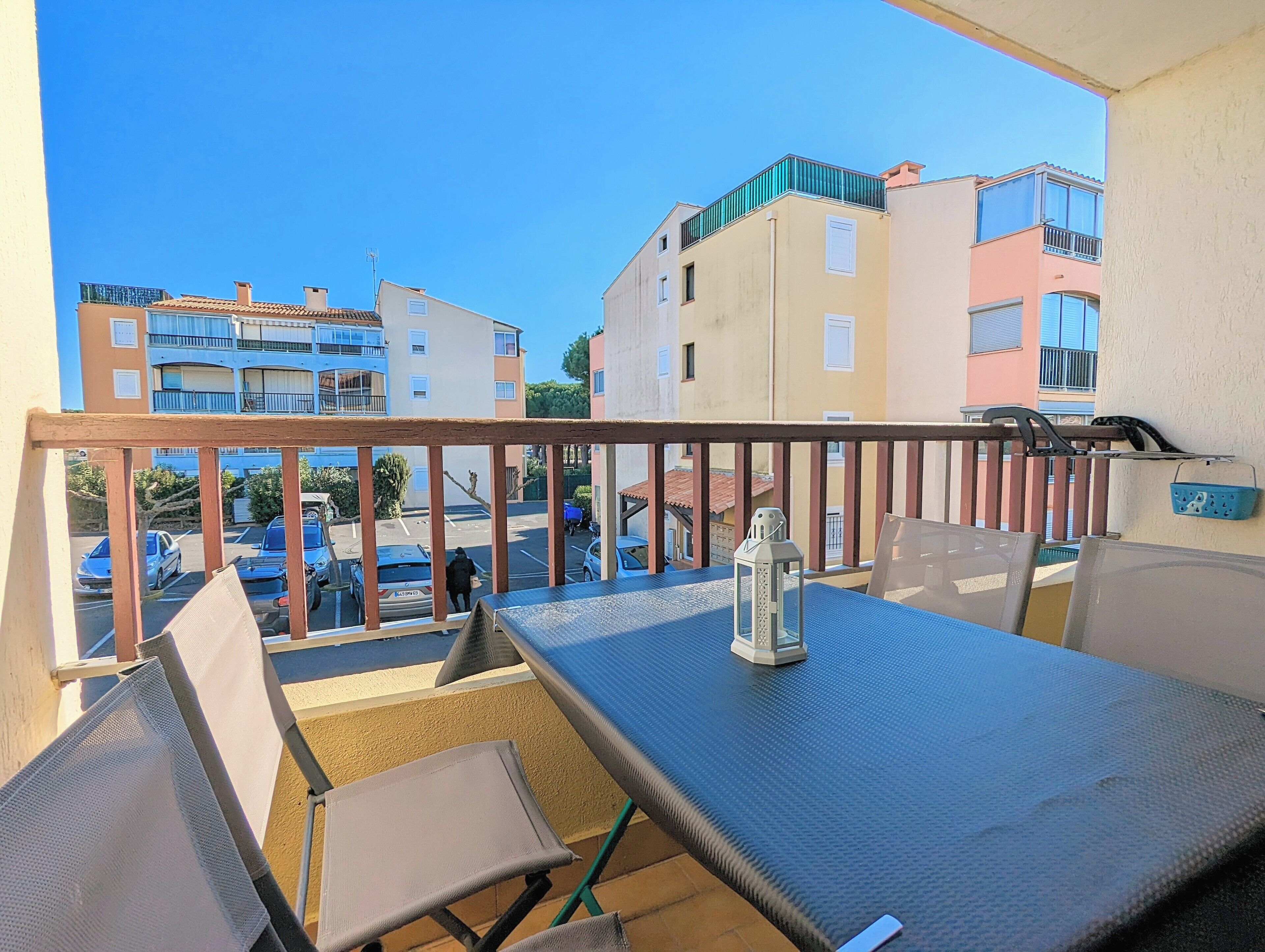 A balcony with a table, chairs, and a lantern.