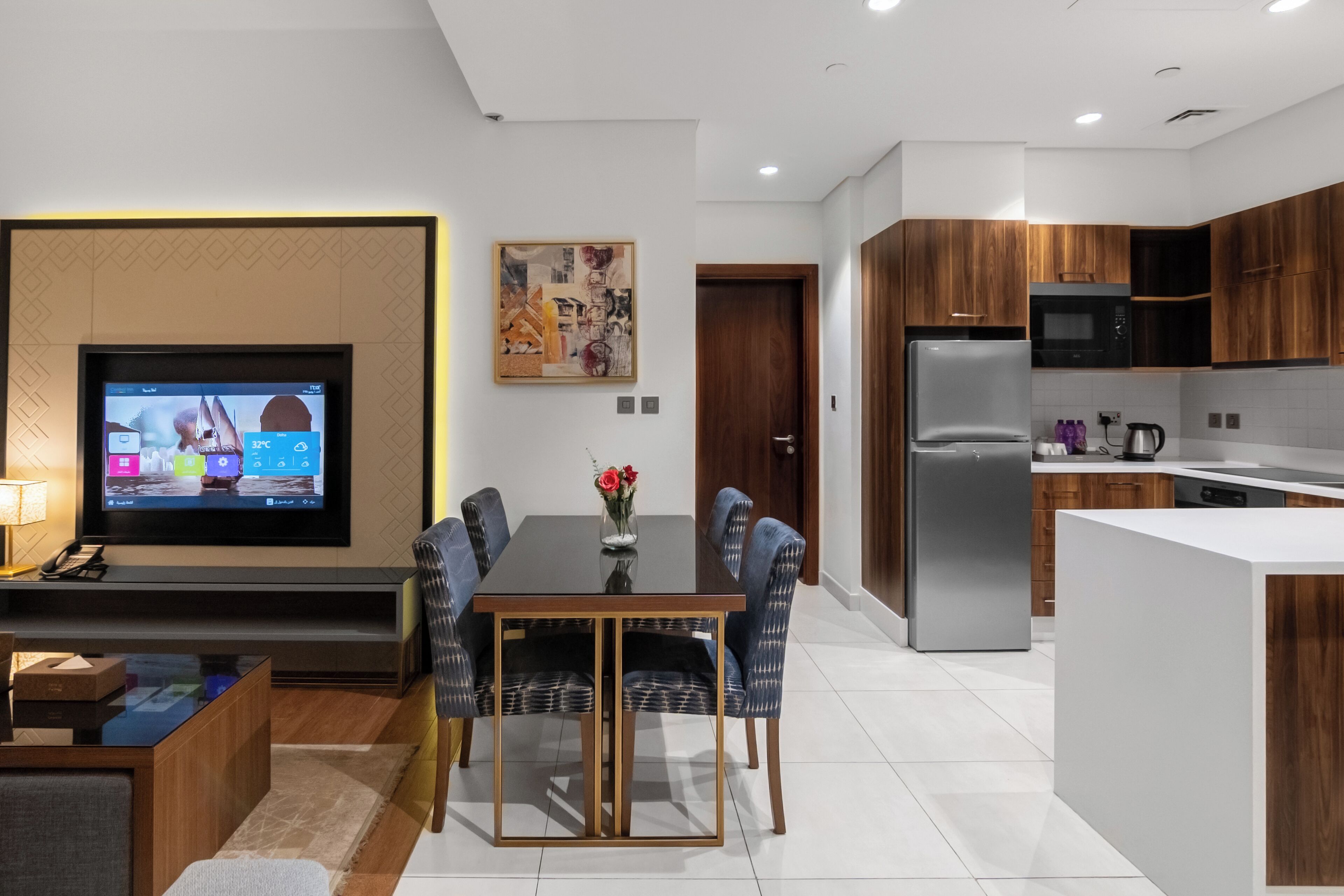 Una cocina moderna con microondas integrado, refrigerador y un comedor con mesa y sillas.