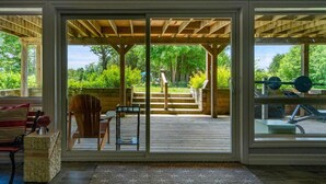 A covered outdoor deck with a wooden pergola, a bench, and a chair.