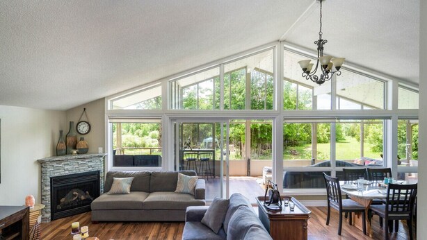 A spacious living room with a fireplace, large windows, and a dining area.