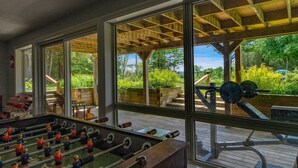A room with a foosball table, large windows, and a view of the outdoors.