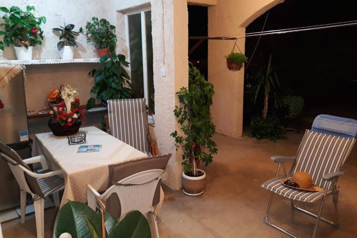 A patio with a table, chairs, potted plants, and a hanging plant.