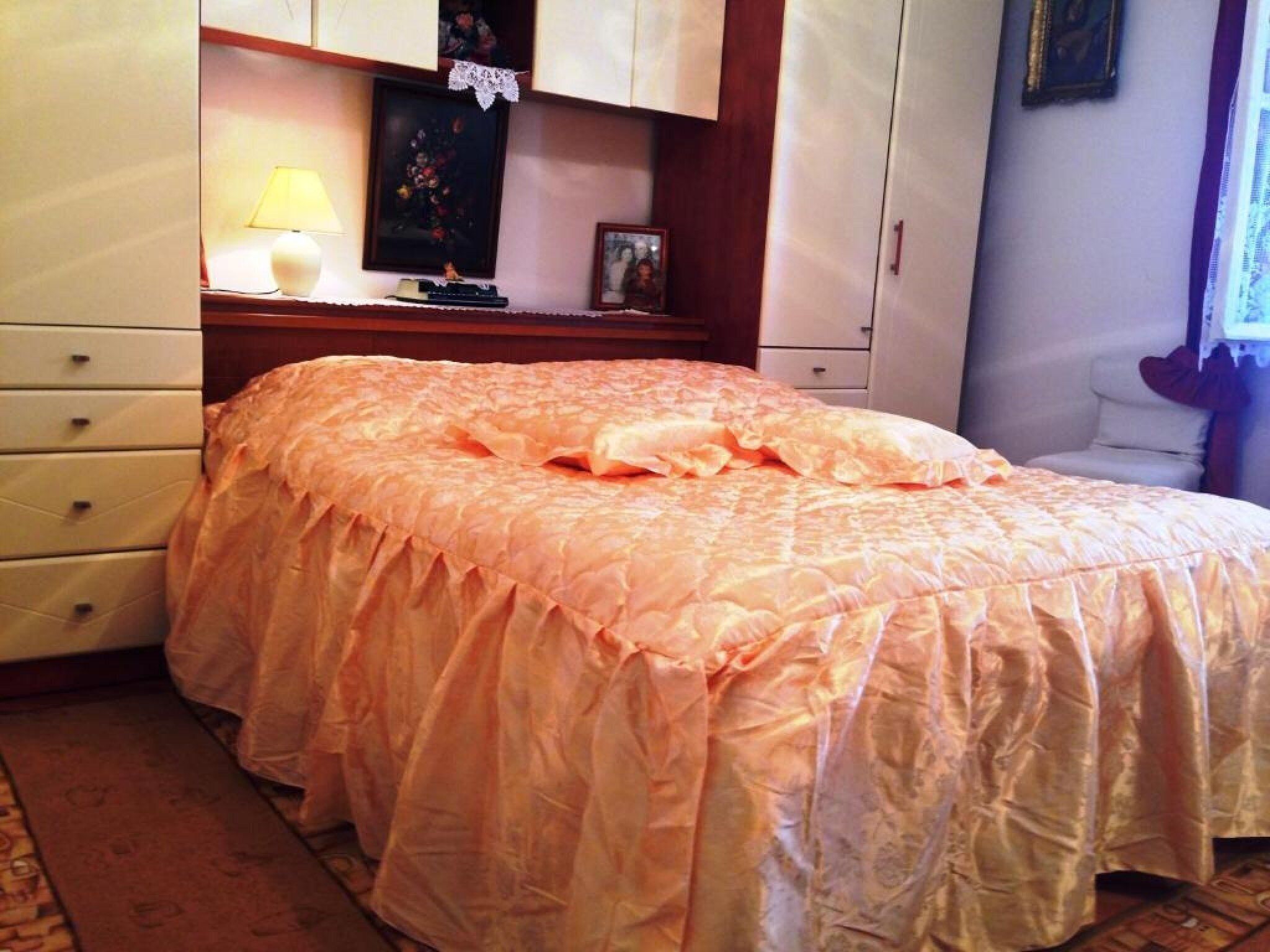 A bedroom with a bed, a nightstand, a lamp, and a dresser.