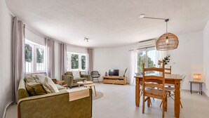 Een moderne woonkamer met een bank, eettafel en televisie.