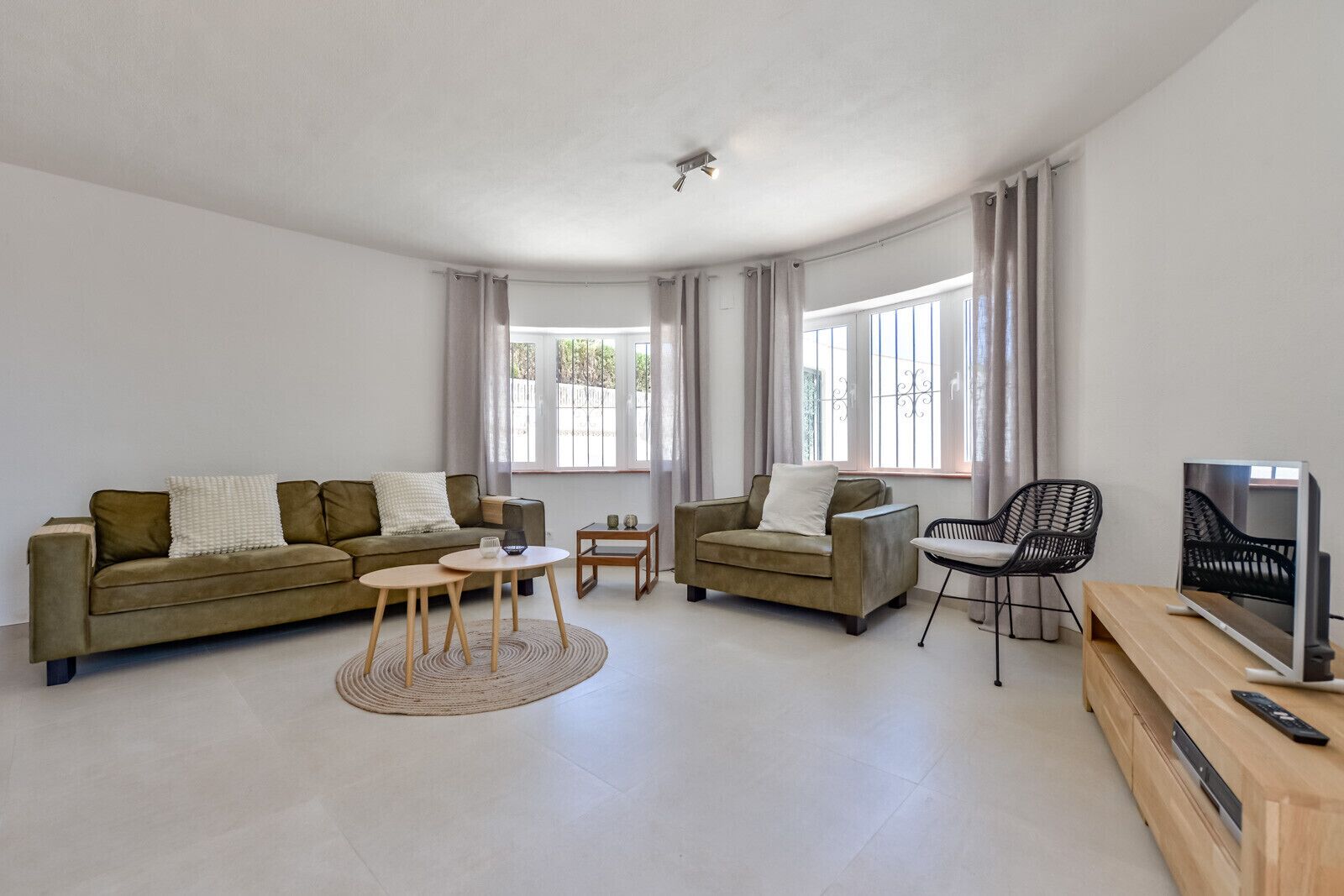 A modern living room with a sofa, armchair, coffee table, side table, and a TV stand.