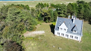 A white house with a grey roof, surrounded by dense greenery and a clear view of the ocean. - Keravel, family home with character and direct access to the sea (Tréflez)