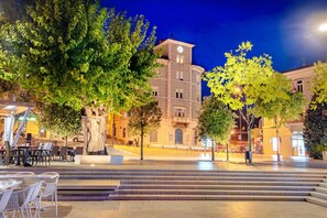 Experience the vibrant atmosphere of this urban square, surrounded by trees and offering outdoor seating for dining.