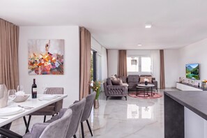 A modern living room with a dining area, a sofa set, and a painting on the wall. - Pool Apartments Crikvenica (Crikvenica)