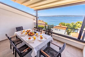 A balcony with a table set for breakfast, overlooking a coastal view.