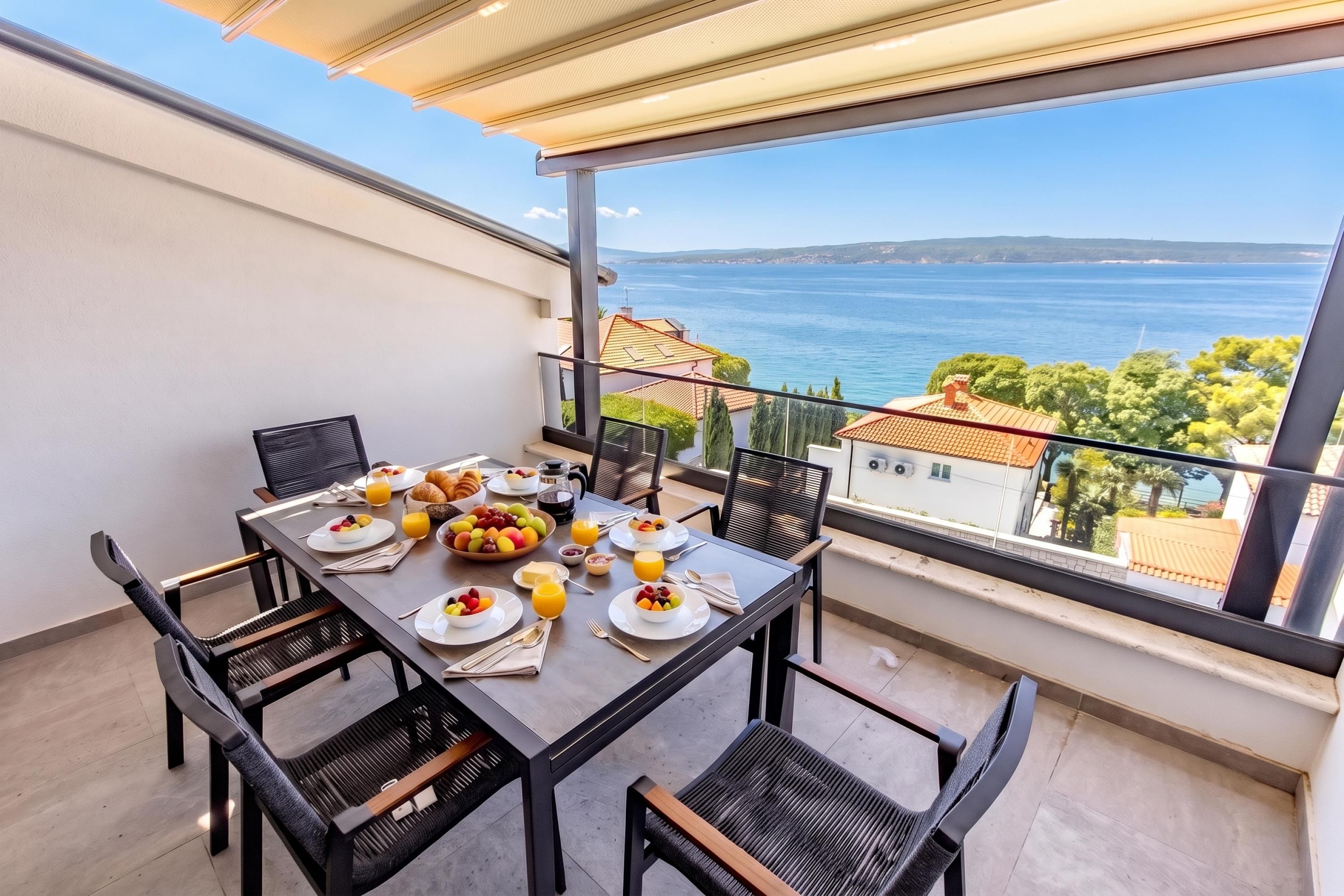 A balcony with a table set for breakfast, overlooking a coastal view.
