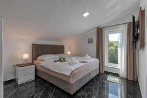 A modern hotel room with a bed, bedside table, lamp, and a window with curtains. - Pool Apartments Crikvenica (Crikvenica)