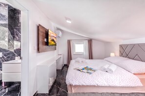 A hotel room with a bed, a desk, a TV, and a window with curtains.