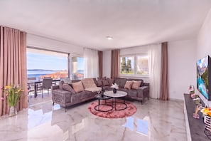 A modern living room with a sectional sofa, a round coffee table, and a large flat-screen TV. - Pool Apartments Crikvenica (Crikvenica)