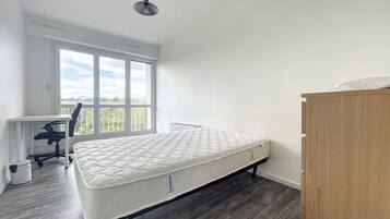 Une chambre avec un lit simple, un bureau et une chaise.
