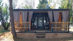 A wooden structure with a covered entrance, a small set of steps leading up to it, and a bamboo fence.