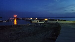 A marina at dusk with boats docked and a light illuminating the area.