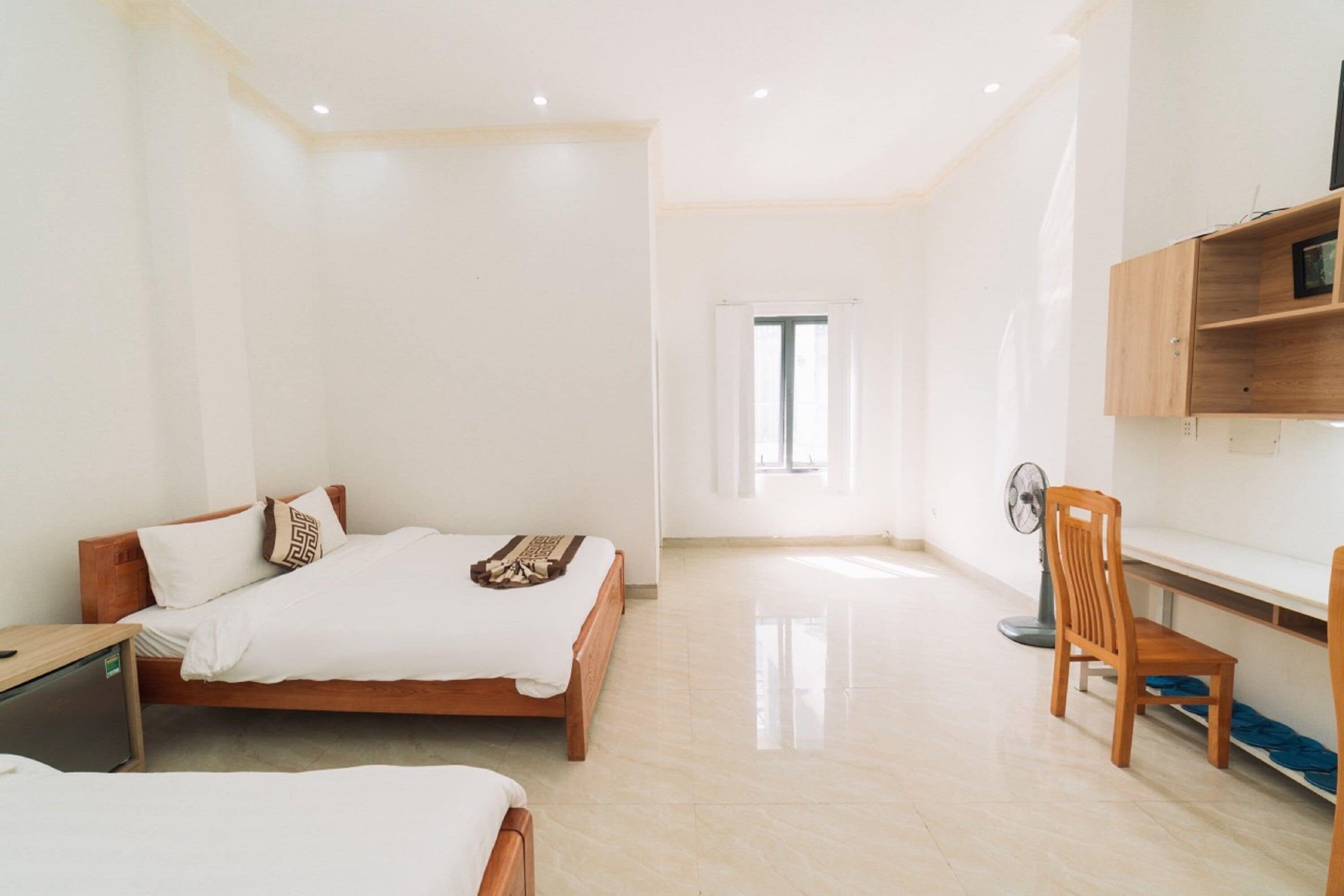 A spacious room with a large bed, a desk, and a chair.
