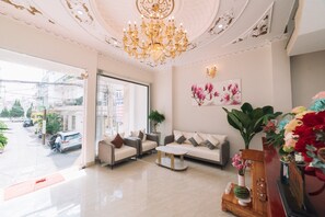 A modern hotel lobby with a chandelier, sofas, a coffee table, and a large window offering a view of the street. - Viet Anh Hotel Da Lat (Xuan Huong - Da Lat)