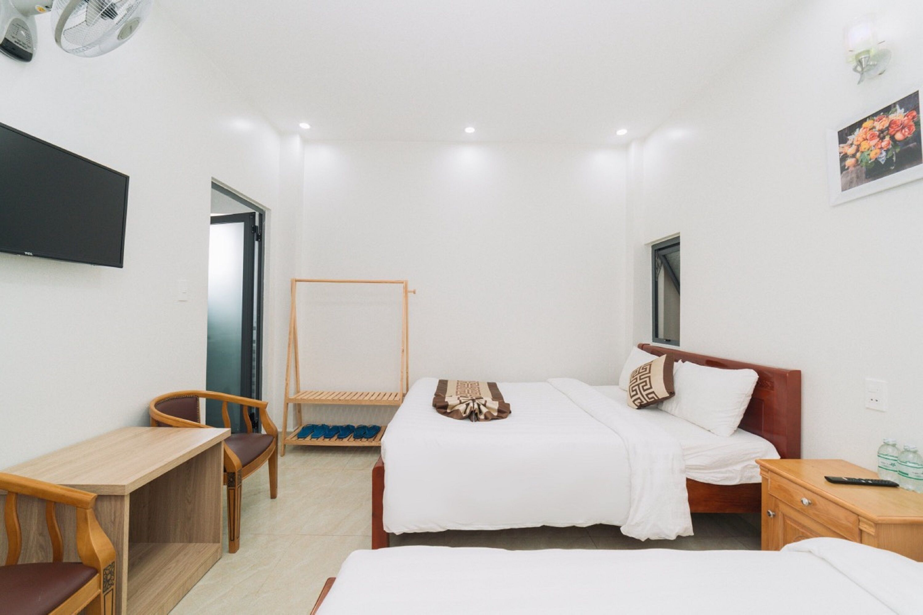 A hotel room with a bed, a desk, a chair, a TV, and a wardrobe.