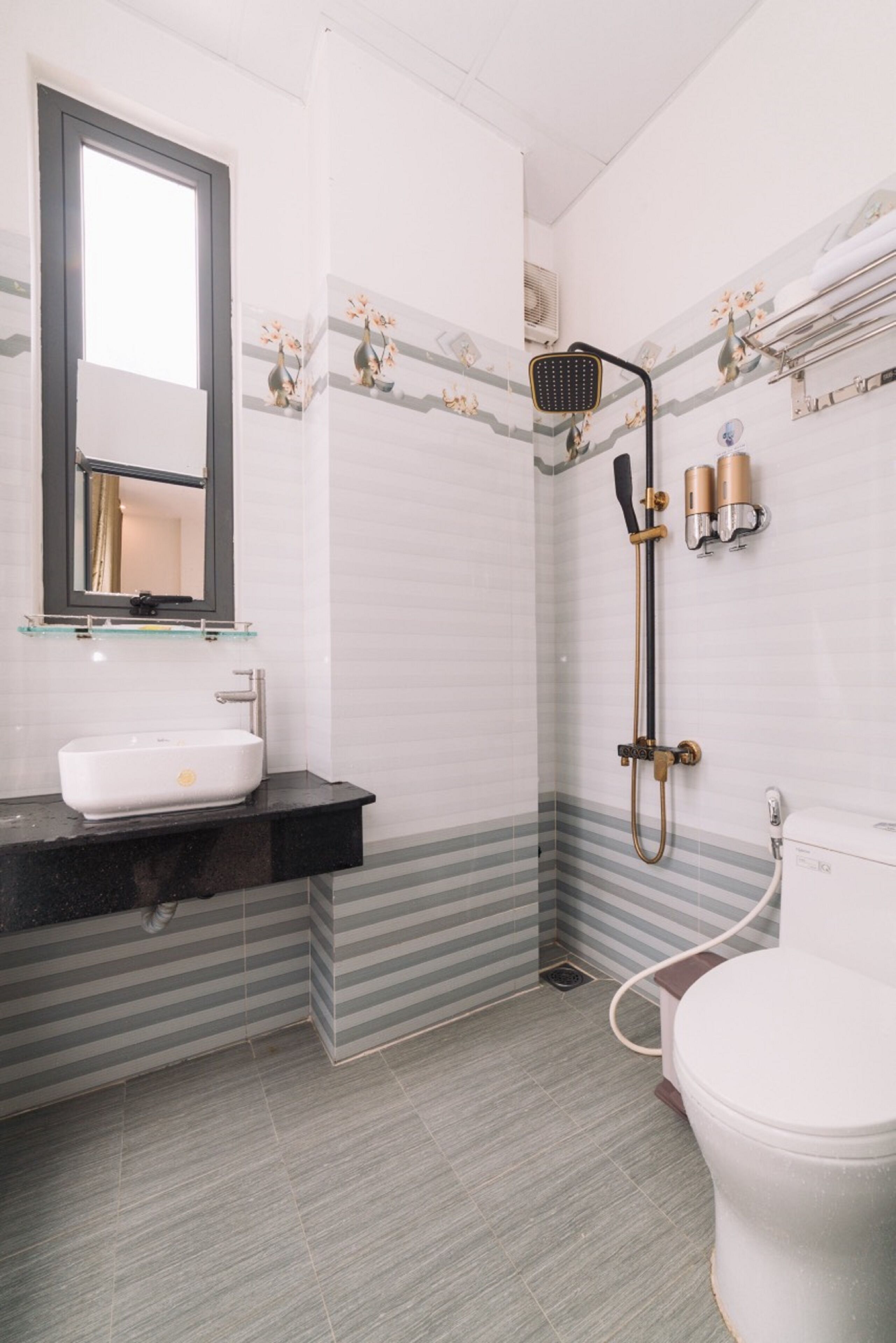 A bathroom with a white sink, a mirror, a shower with a handheld showerhead, and a toilet.