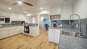 A modern kitchen with white cabinets, granite countertops, a built-in oven, and a stainless steel sink.