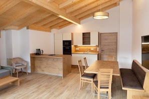 A modern kitchen with wooden cabinets, a central island, and a dining area with a wooden table and chairs.