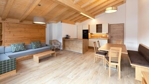 A modern interior with a wooden ceiling, a kitchen area, a dining table with chairs, and a seating area with a sofa and cushions. - Apartment in Kleinarl near Ski Slopes (Kleinarl)