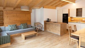 A modern interior with a wooden ceiling, a sofa with patterned cushions, a wooden dining table, and a kitchen area. - Apartment in Kleinarl near Ski Slopes (Kleinarl)