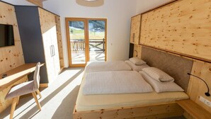 A bedroom with a large bed, wooden furniture, and a view of a deck. - Apartment in Kleinarl near Ski Slopes (Kleinarl)