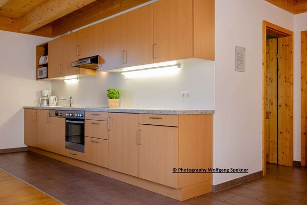 A modern kitchen with wooden cabinets, a built-in oven, and a microwave. - Chalet in Carinthia with Sauna near Ski Slopes (Sankt Gertraud-Weinebene)
