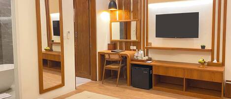 A hotel room with a bed, a desk with a chair, a television, and a mirror.