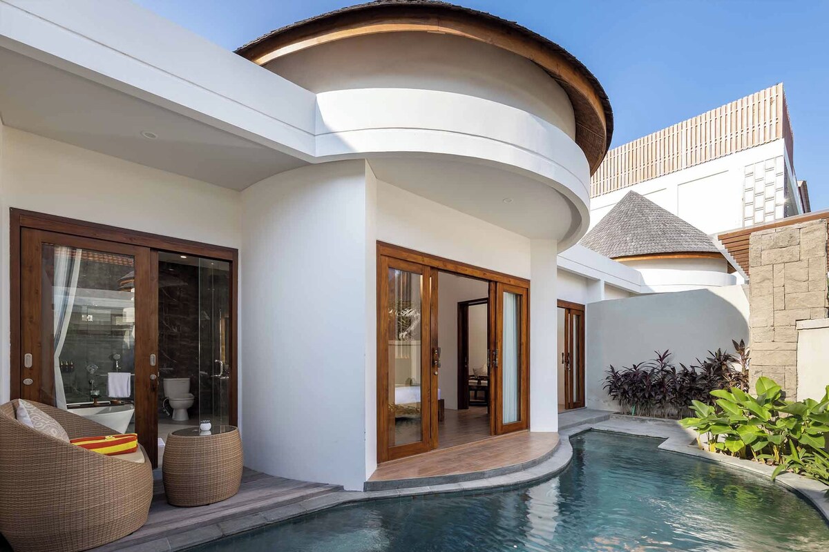 A modern villa with a swimming pool, large glass doors, and a curved roof.