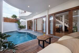 A modern outdoor living area with a pool, wooden deck, and a dining area.
