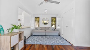Un intérieur moderne avec un canapé, un ventilateur de plafond, un miroir et un tapis à motifs.