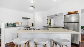 Une cuisine moderne dotée d’un îlot central, d’appareils électroménagers en acier inoxydable et d’un coin bar avec des tabourets.