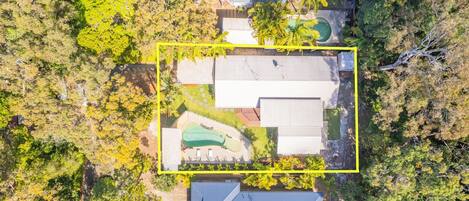 Vista aérea de uma propriedade residencial com piscina, vários edifícios e vegetação ao redor.