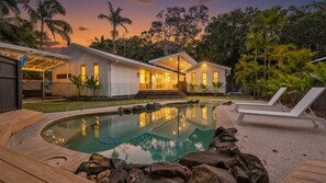 A residential property with a swimming pool, outdoor seating, and a well-maintained garden.