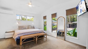 A bedroom with a bed, a bedside table, a chair, a window, and a ceiling fan.