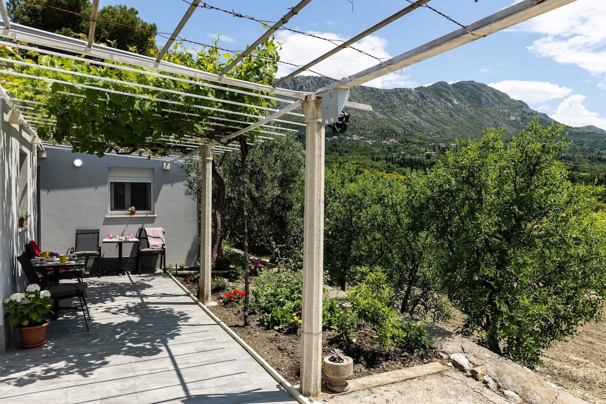 Un patio con una pérgola, mobiliario exterior y vistas a las montañas.