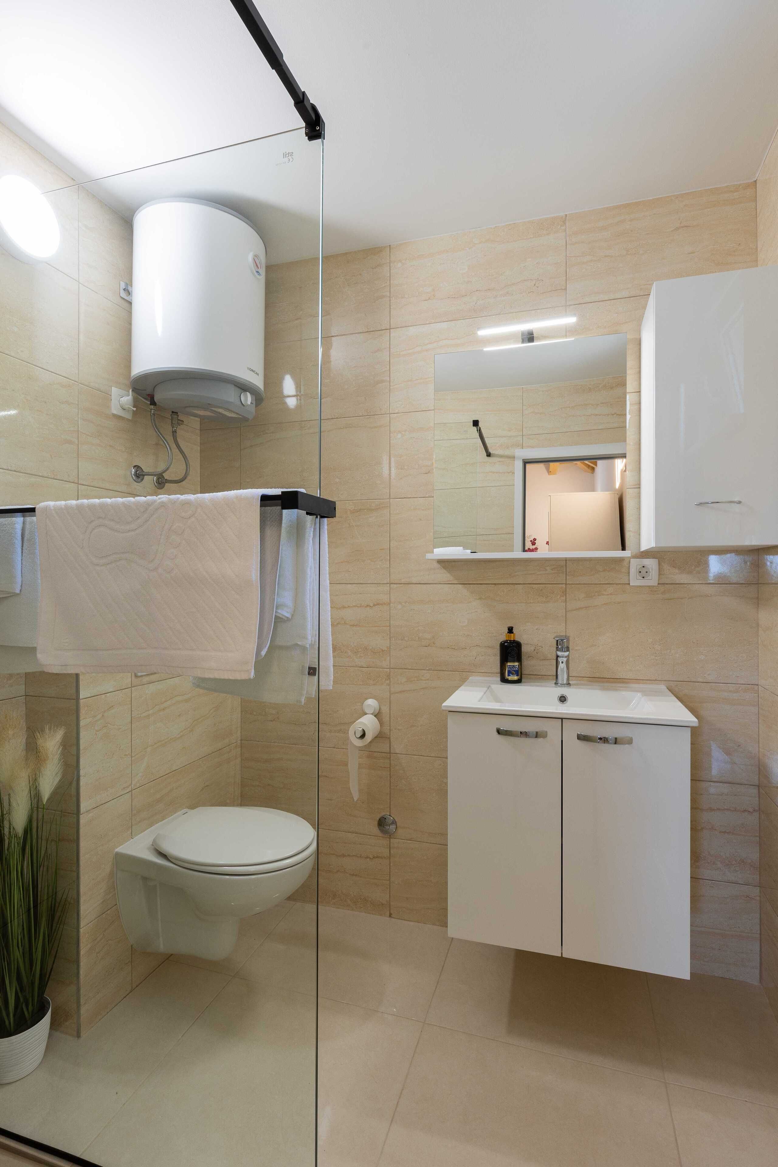 Une salle de bain moderne équipée de toilettes, d’un lavabo et d’une douche à parois en verre.