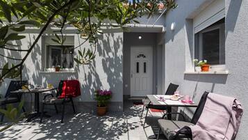 Un patio al aire libre con una mesa, sillas, una planta en maceta y una puerta.
